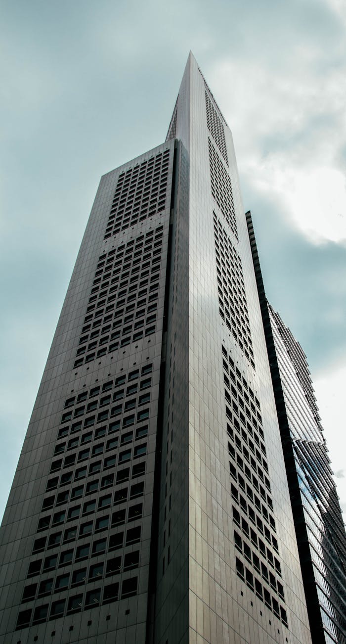 A low angle view of a skyscraper reaching into the cloudy sky, showcasing modern architecture.